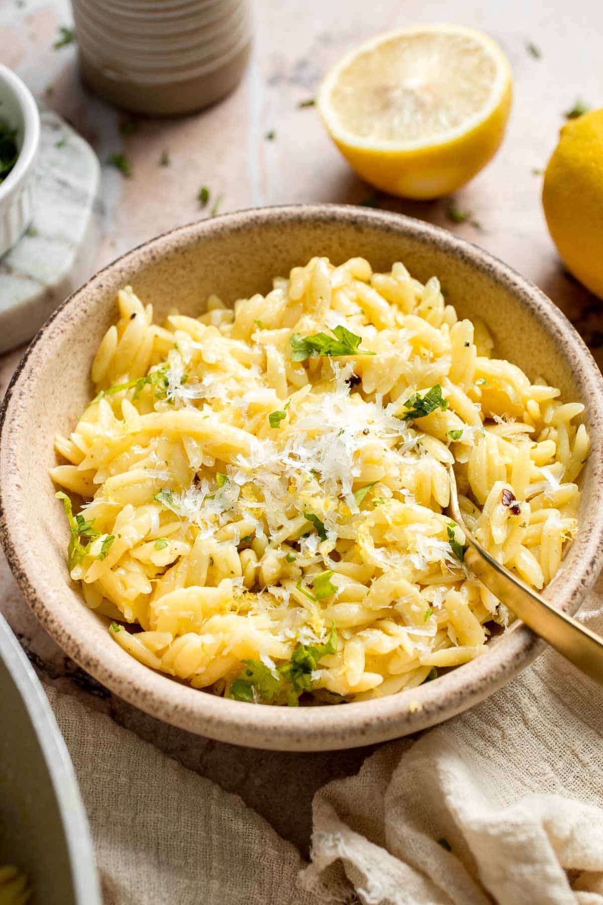 Bowl of creamy Lemon Orzo topped with Parmesan cheese and fresh parsley.