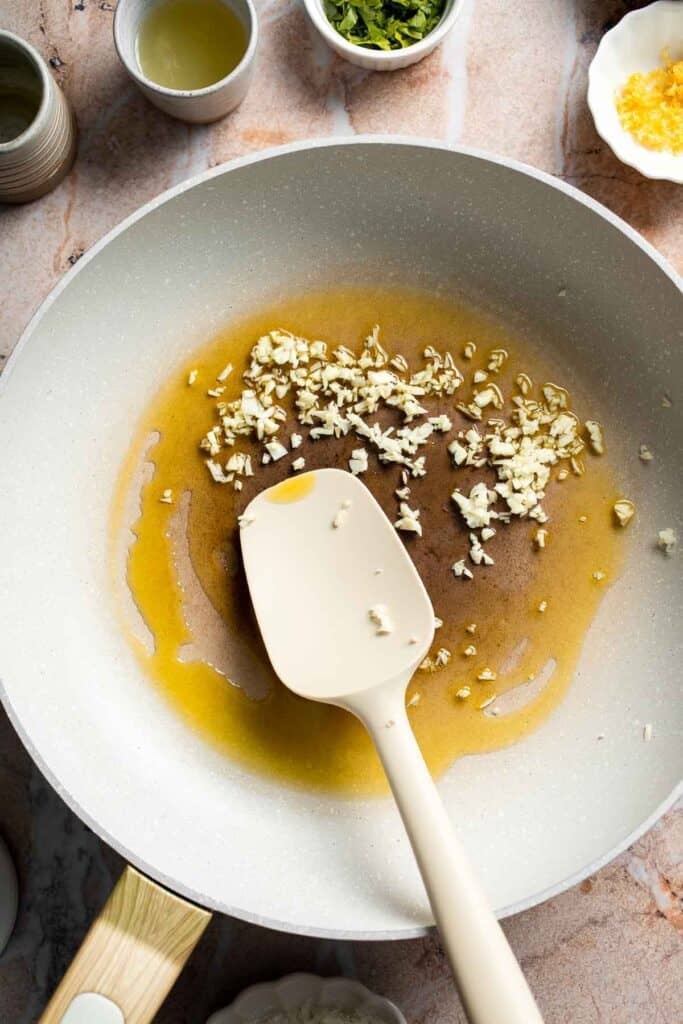 Garlic cooking in olive oil and butter in a large skillet.
