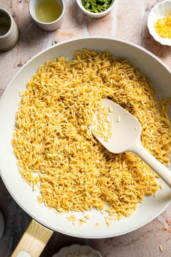 Toasting orzo in a skillet until lightly golden and fragrant.