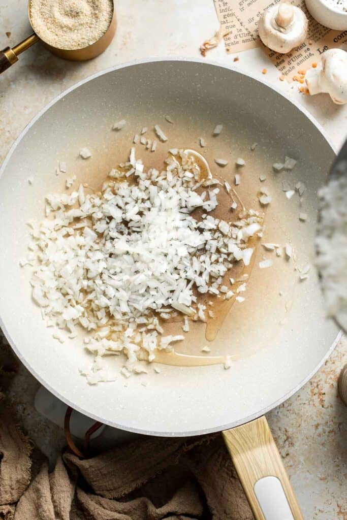 Diced onion and minced garlic cooking in a skillet.