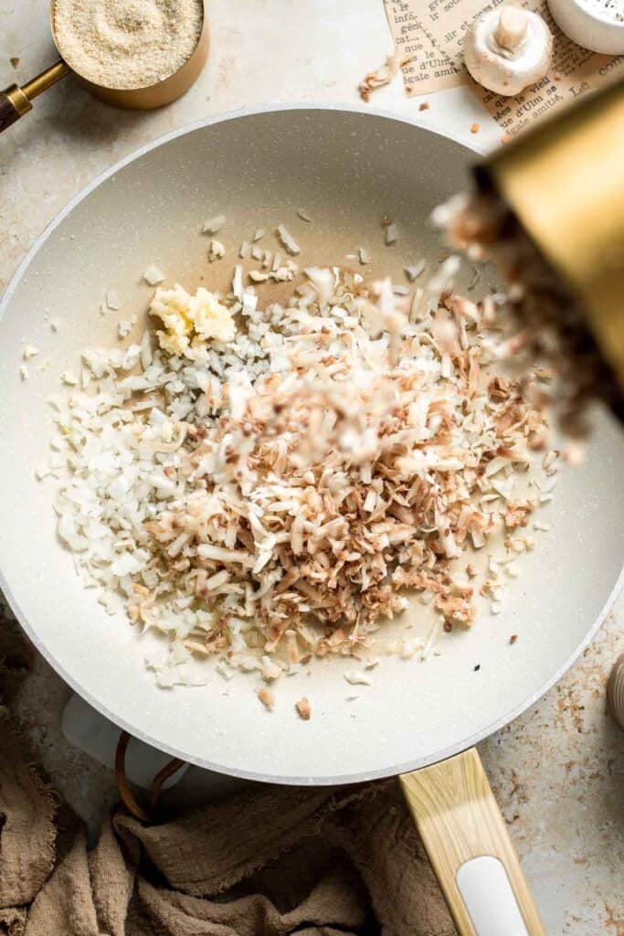Adding finely grated mushrooms to sautéed onion and garlic.