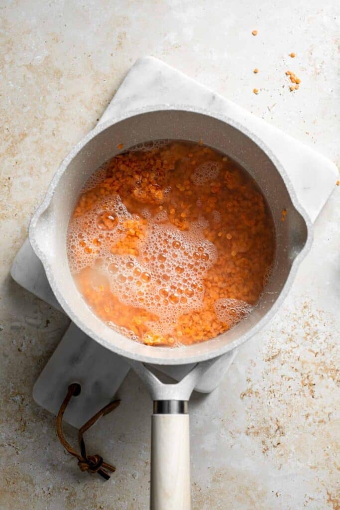 Red lentils simmering in water until soft and tender.
