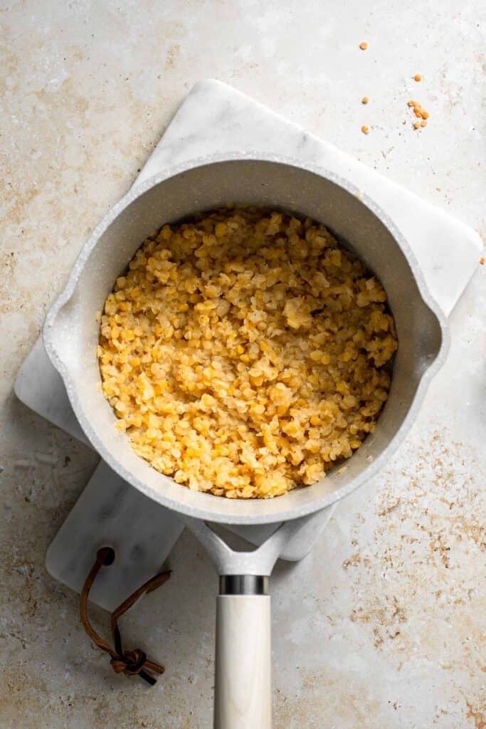 Cooked red lentils thick and tender in a saucepan.