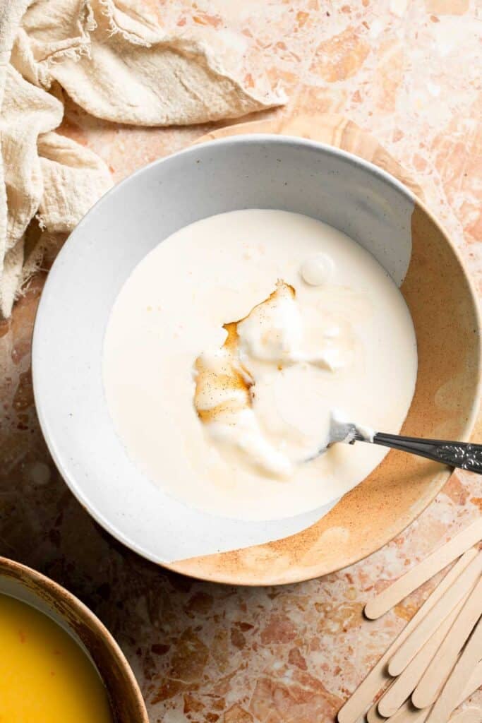 Greek yogurt and heavy cream in a mixing bowl for the vanilla cream layer.