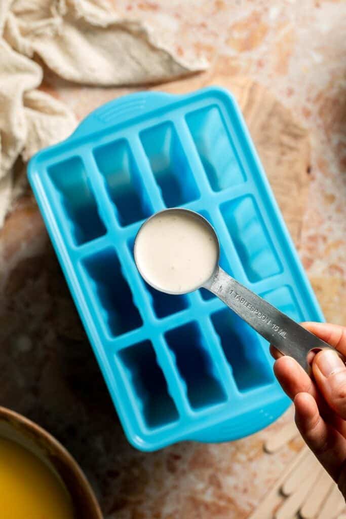 Adding the vanilla cream mixture to a blue popsicle mold.