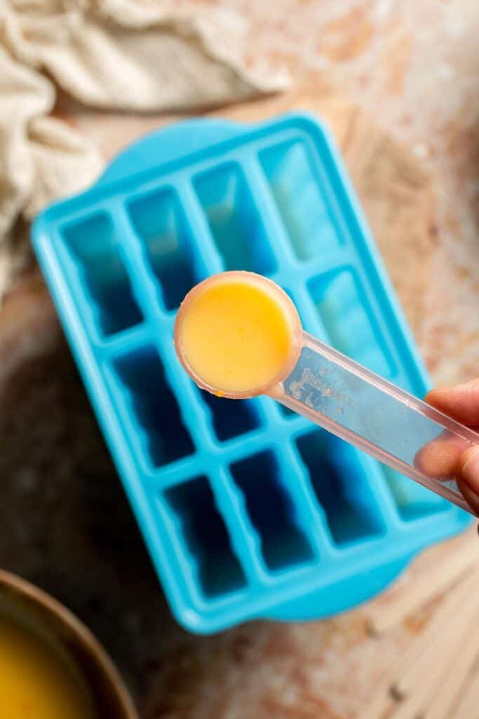 Adding a layer of orange mixture to the popsicle molds.