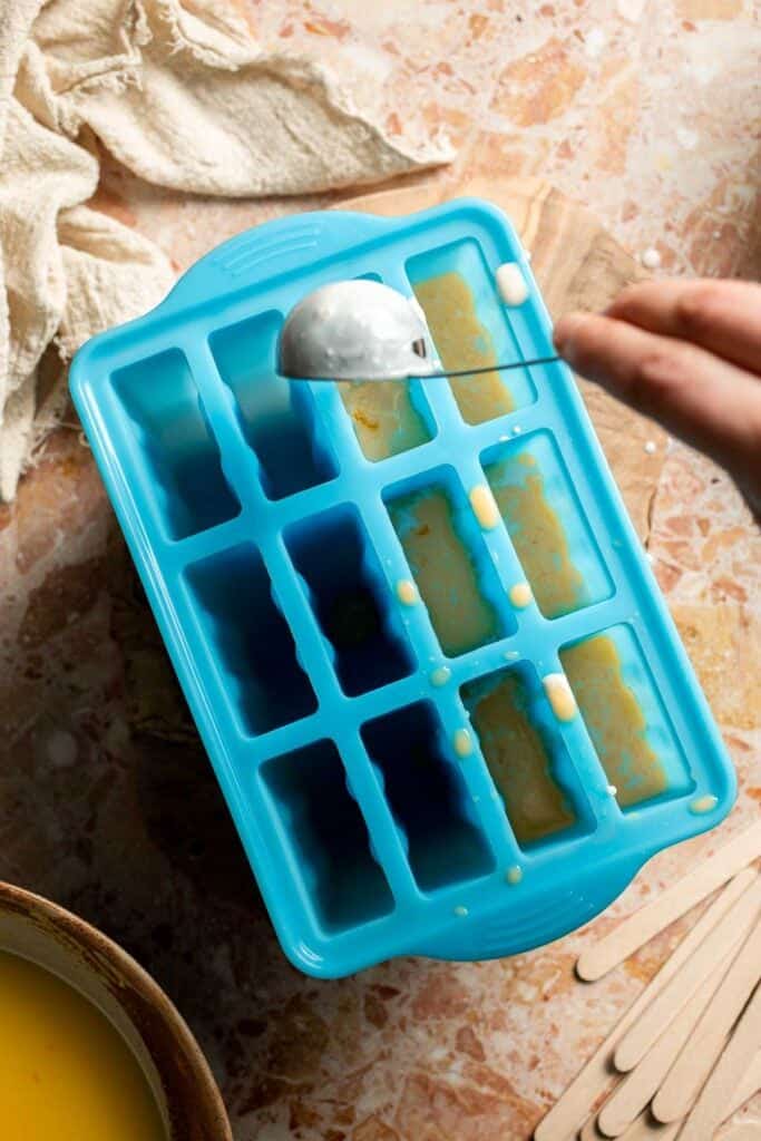 Layered orange and cream mixtures in popsicle molds.
