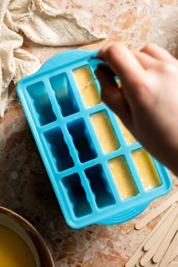 Swirling the orange and cream mixtures together in the popsicle molds.