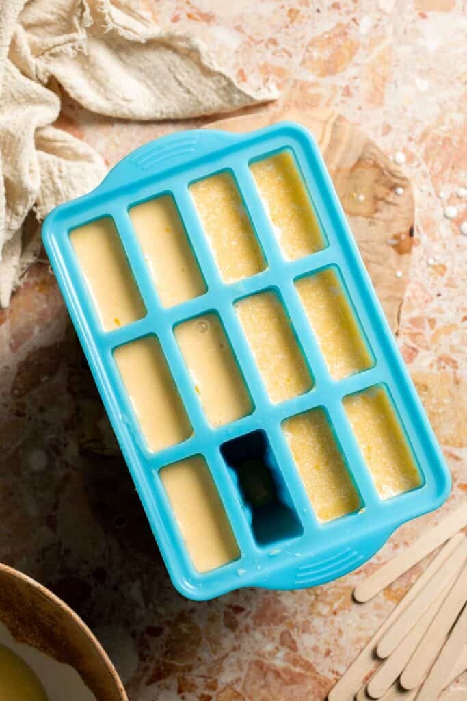 Popsicle molds filled with creamy orange creamsicle mixture.