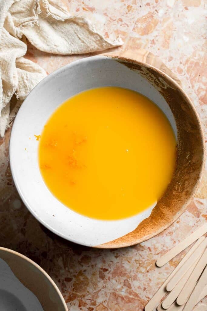 Orange juice and orange zest in a mixing bowl for homemade creamsicles.