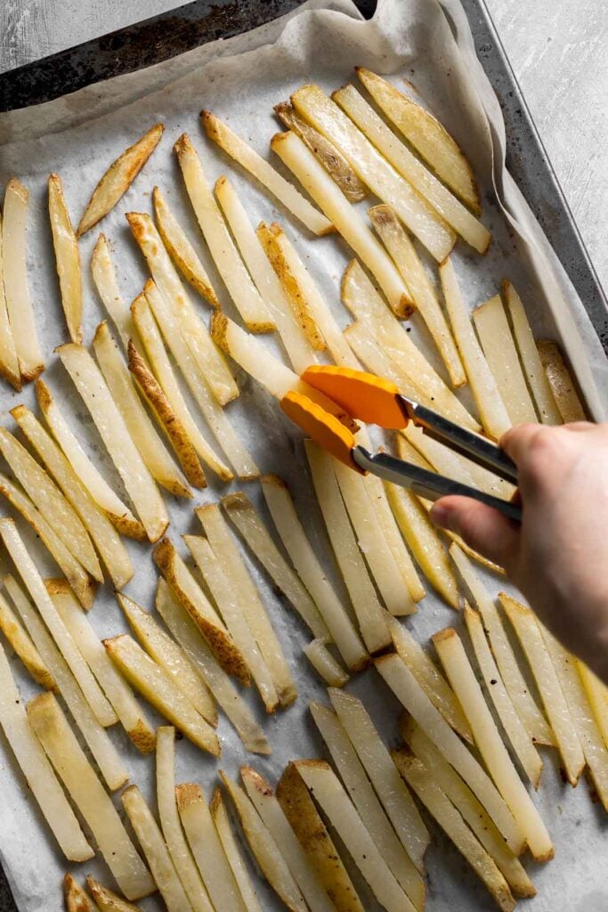 Flipping oven baked French fries halfway through baking.