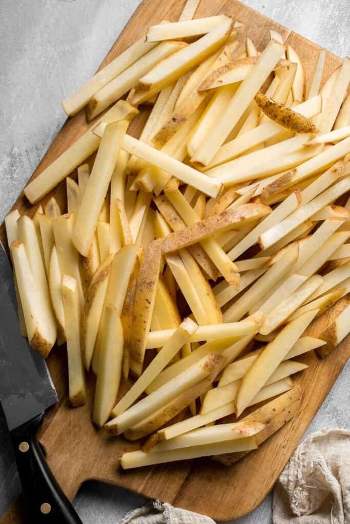 Freshly cut russet potatoes sliced into French fries.