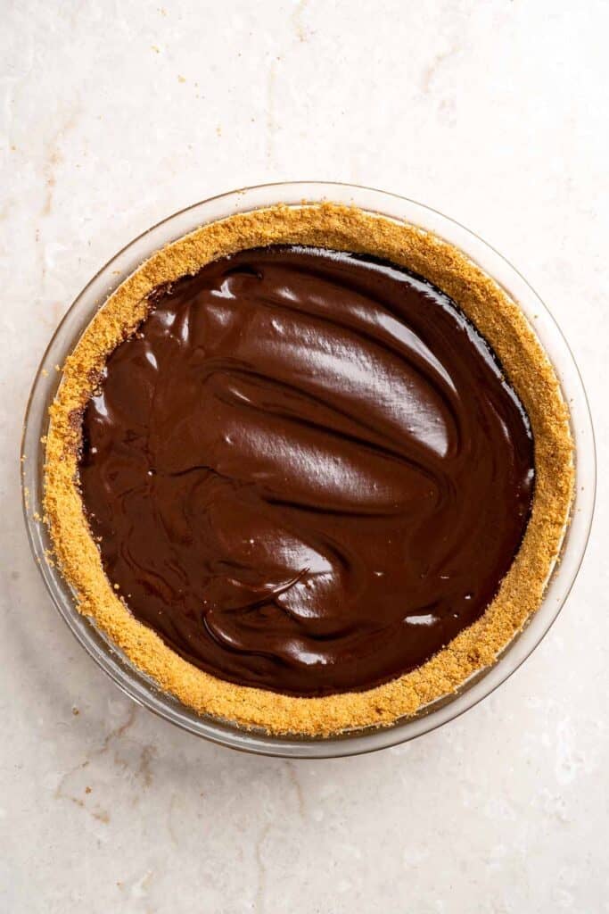 Chocolate ganache spread evenly inside the homemade graham cracker pie crust.