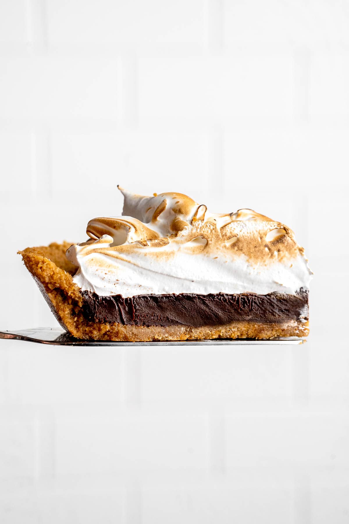 Single slice of S'mores Pie with chocolate ganache filling and fluffy toasted marshmallow topping.