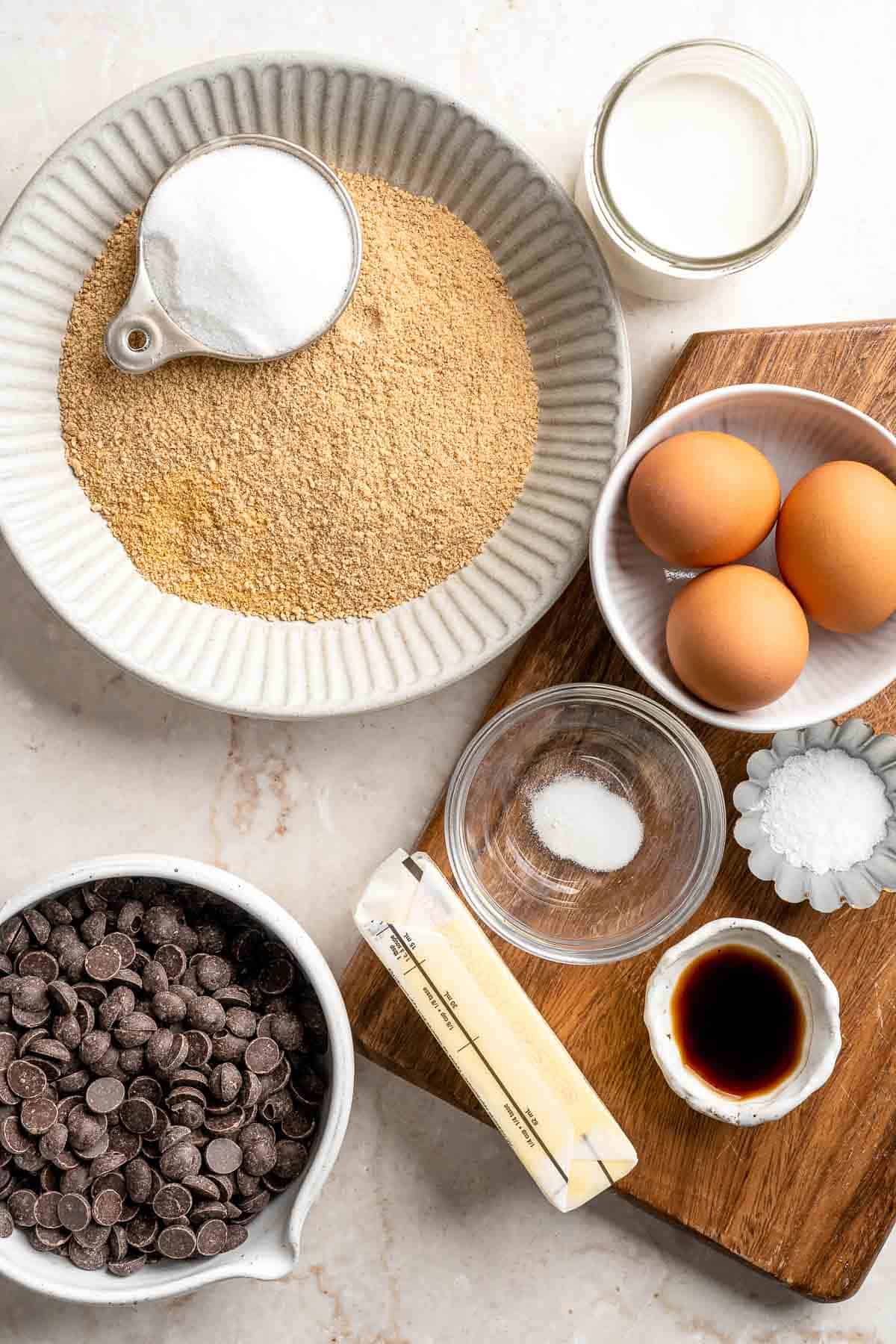 Ingredients for homemade S'mores Pie including graham crackers, chocolate, heavy cream, butter, eggs, sugar, and vanilla.