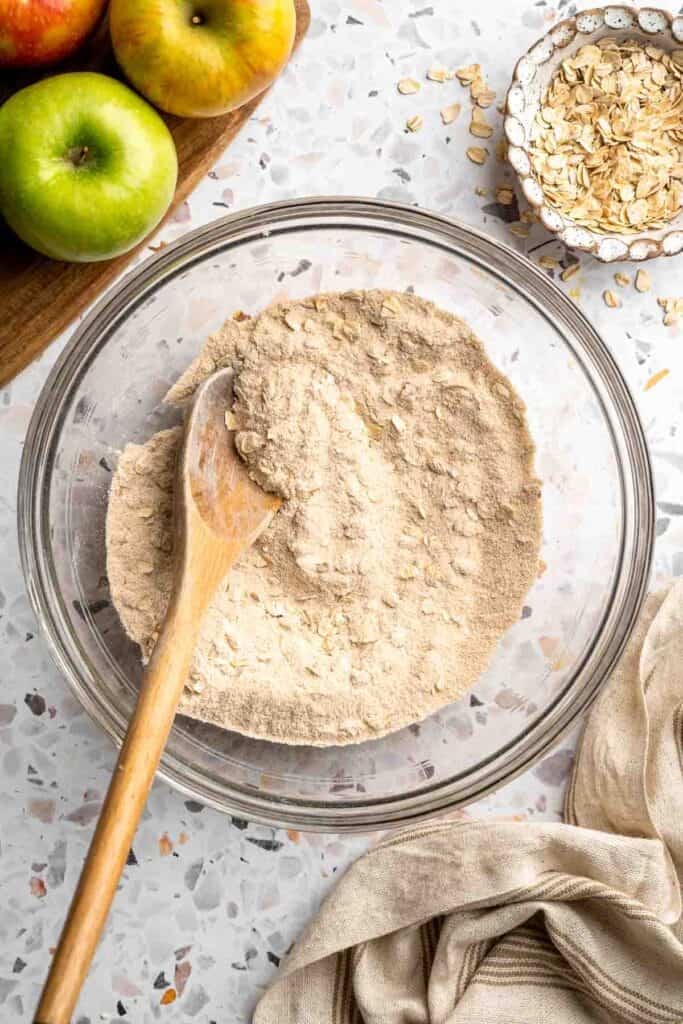 Flour, oats, and spices being combined in a glass bowl for the crumble topping