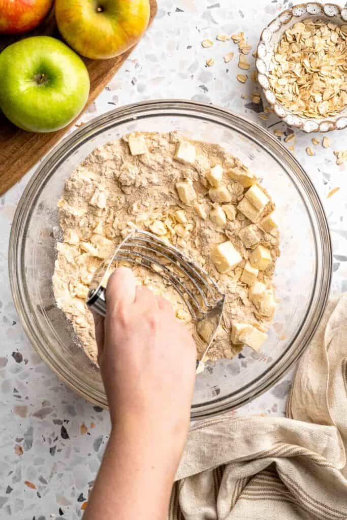 Using a pastry cutter to cut butter into the crumble topping mixture