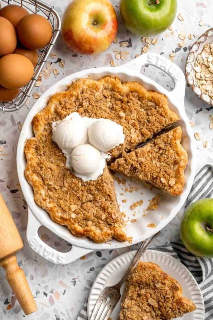 Sliced apple crumble pie with a golden, crisp crumble topping topped with vanilla ice cream