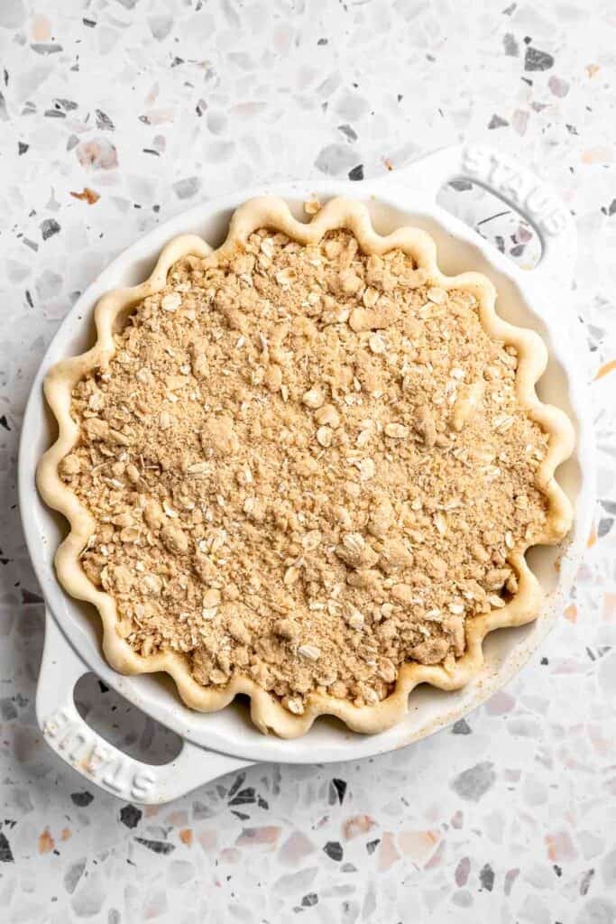 Crumble topping sprinkled evenly over apple filling in a pie crust