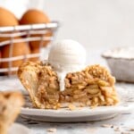 Apple crumble pie slice served with a scoop of vanilla ice cream and golden oat crumble topping.