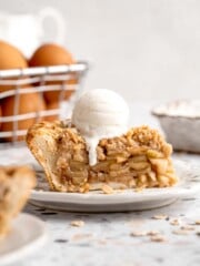 Apple crumble pie slice served with a scoop of vanilla ice cream and golden oat crumble topping.