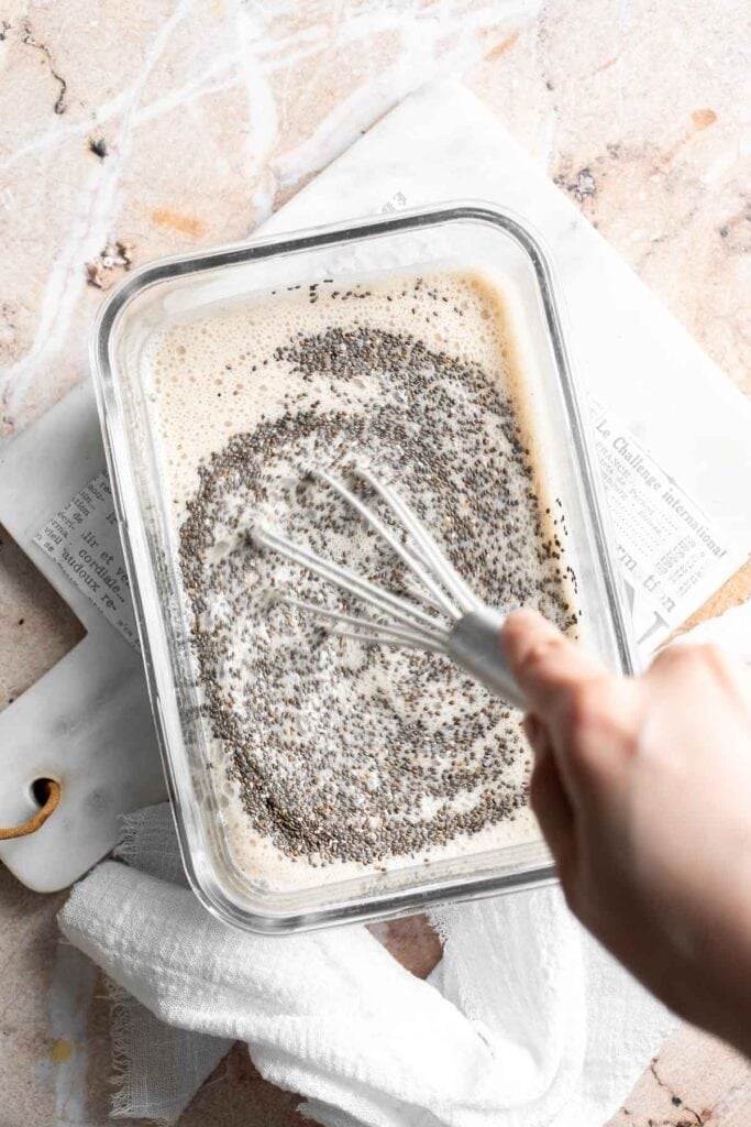 Chia seeds being whisked into banana mixture in a glass container