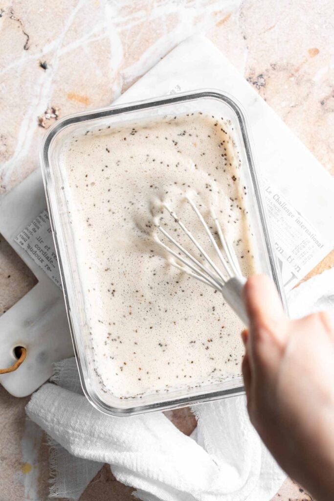 Chia seed and banana mixture being whisked together in a glass container to break up any lumps