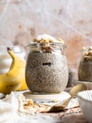 Banana chia pudding in a jar topped with granola, nuts, banana slices, and shredded coconut