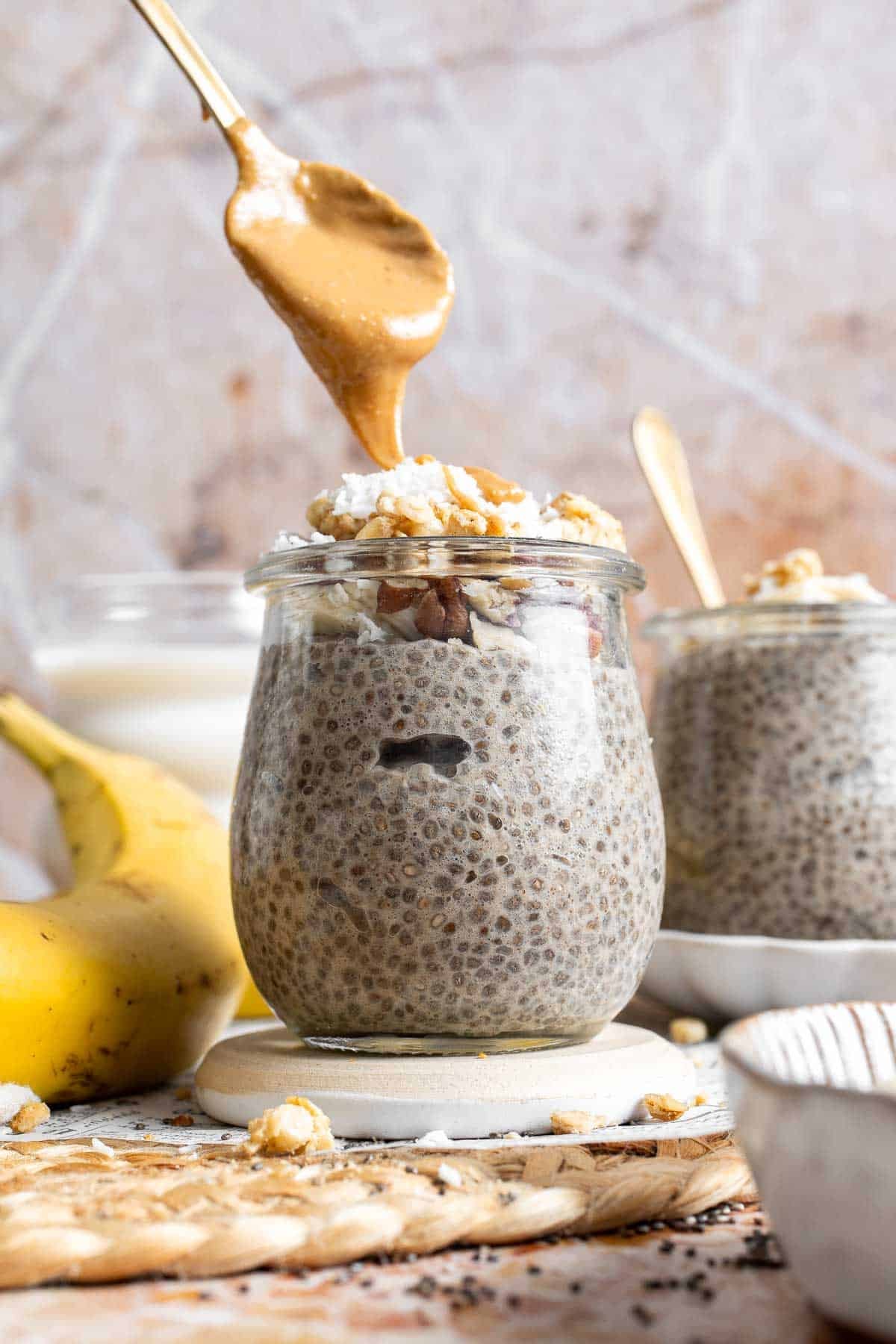 Peanut butter being drizzled over banana chia pudding in a jar