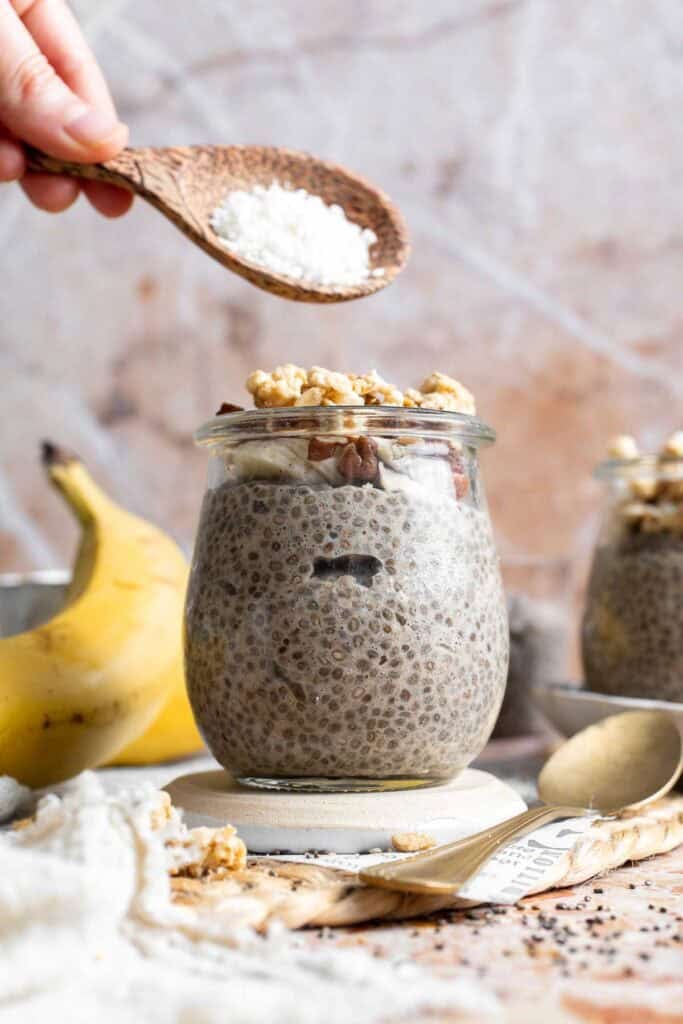 A spoonful of shredded coconut being added to banana chia pudding