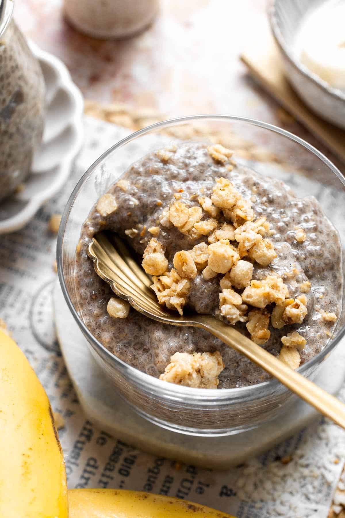 Overhead view of banana chia pudding in a bowl topped with granola, nuts, and a spoon