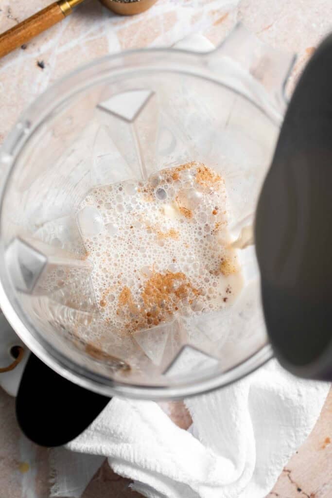Milk being poured into a blender with bananas and other ingredients