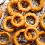 Crispy Beer Battered Onion Rings cooling on a wire rack after frying.