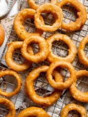 Crispy Beer Battered Onion Rings cooling on a wire rack after frying.