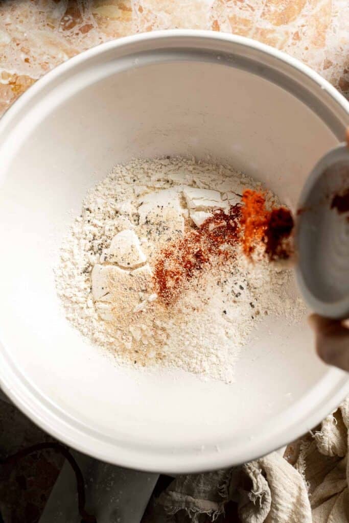 Adding paprika and garlic powder to the flour mixture.