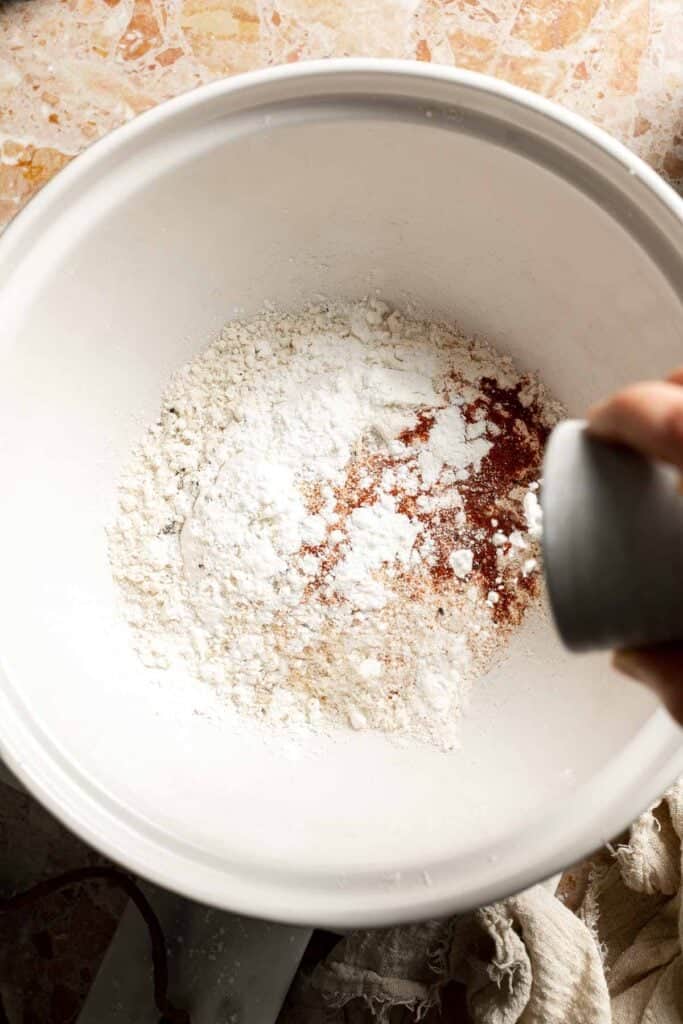Seasoning the flour mixture with salt and black pepper.