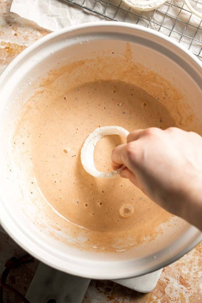 Dipping a floured onion ring into the beer batter.