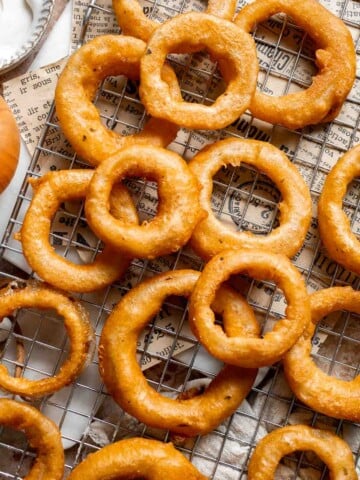 Crispy Beer Battered Onion Rings cooling on a wire rack after frying.