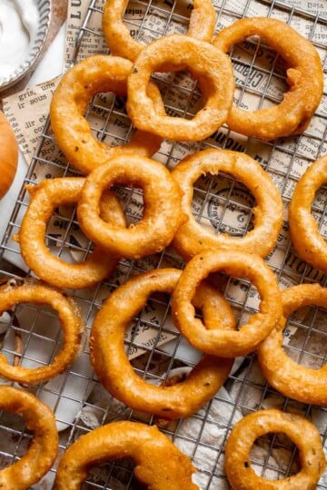 Crispy Beer Battered Onion Rings cooling on a wire rack after frying.