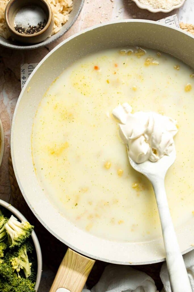 Sour cream being added to sauce in a skillet