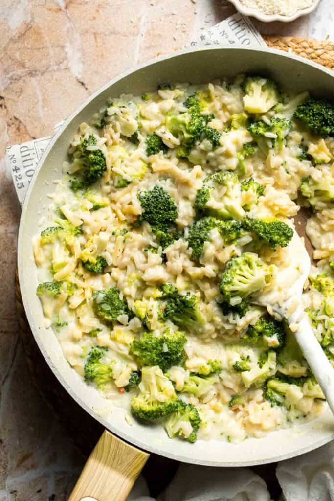 Broccoli rice casserole filling mixed with melted cheddar cheese in a skillet