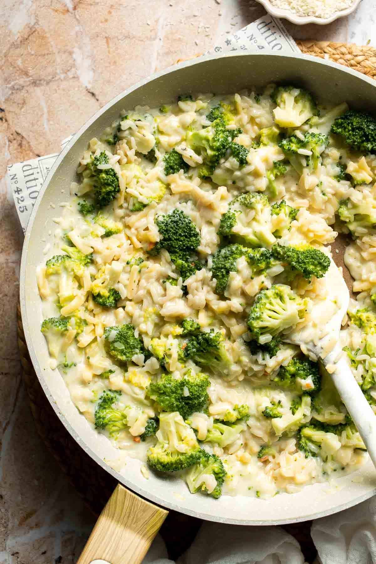 Broccoli rice casserole filling mixed with melted cheddar cheese in a skillet