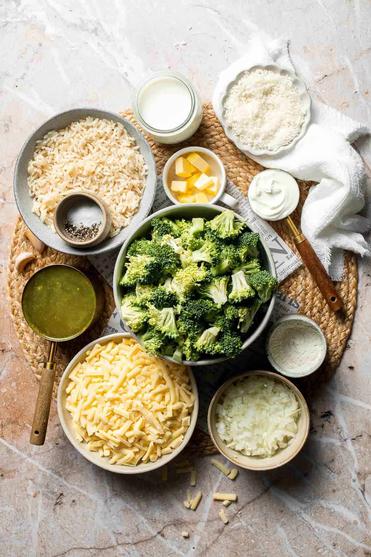 Ingredients for cheesy broccoli rice casserole including broccoli, rice, cheddar cheese, and sour cream arranged on a counter