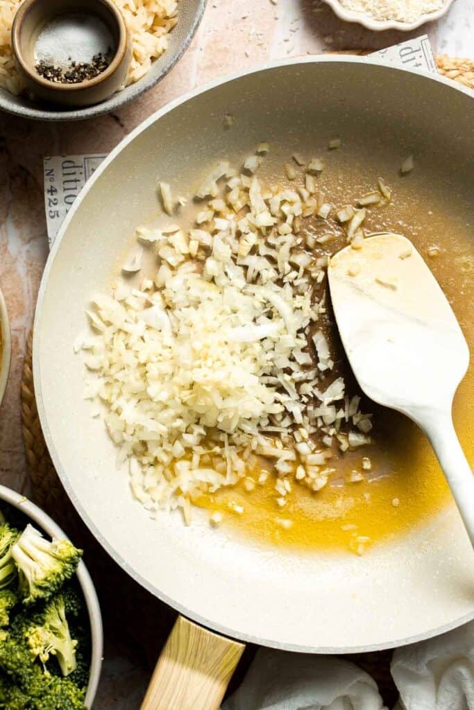 Shallot and garlic being sautéed in melted butter in a skillet