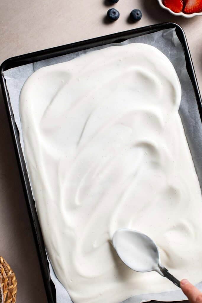 Yogurt mixture spread into an even layer on a parchment-lined baking tray