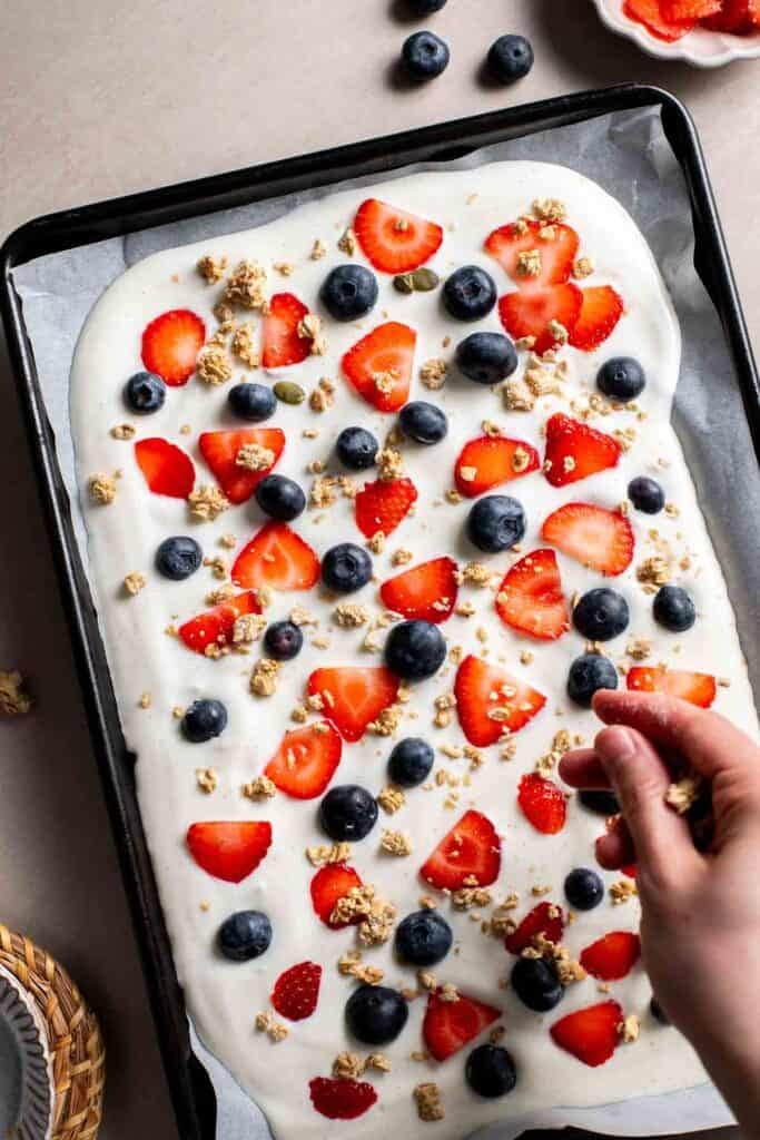 Adding granola on top of the yogurt and berries