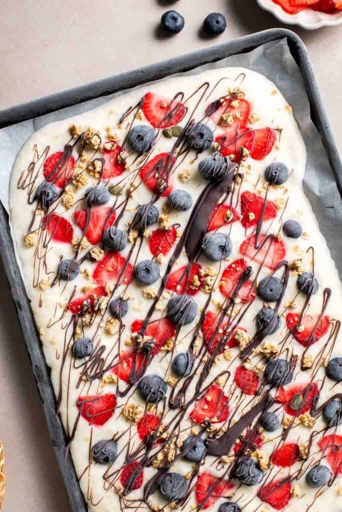 Overhead view of frozen yogurt bark drizzled with chocolate after freezing