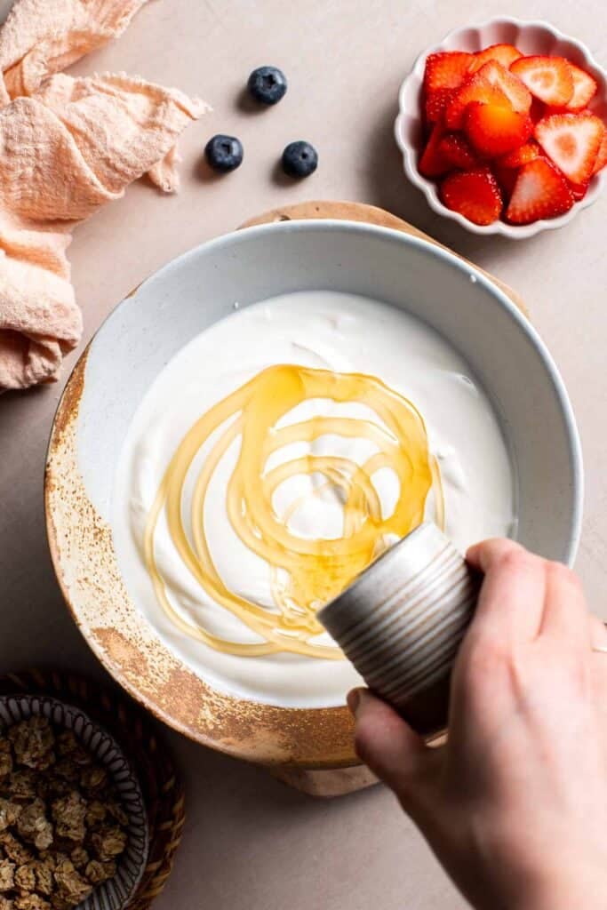 Honey being poured into a bowl of Greek yogurt