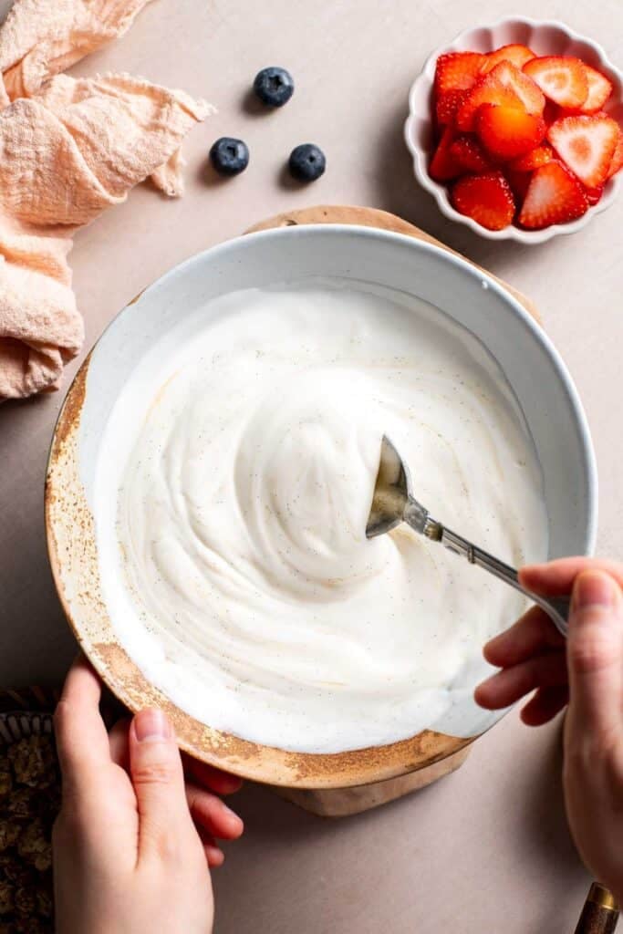 Greek yogurt mixture being stirred smooth in a white bowl