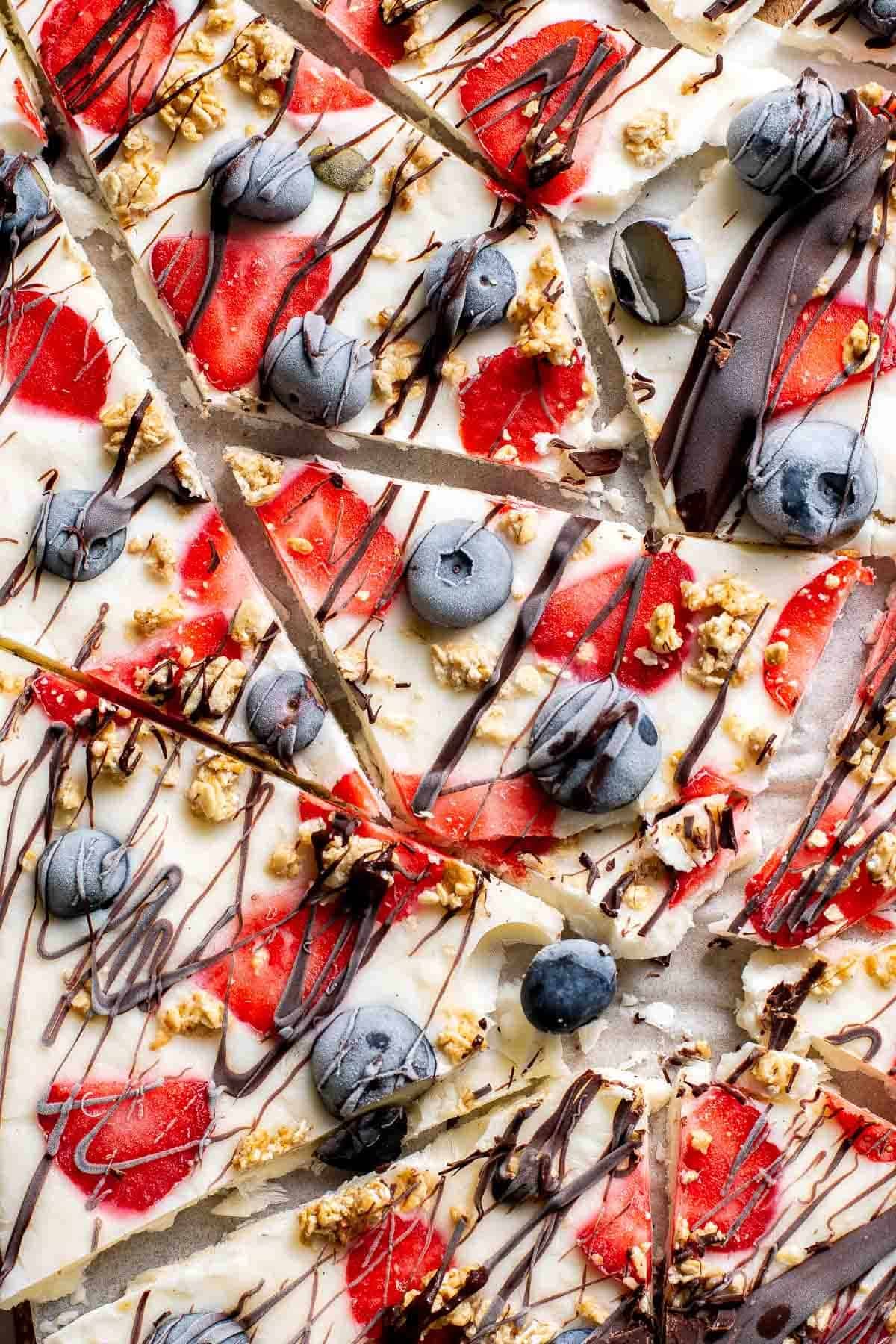Close-up of frozen yogurt bark broken into pieces showing berries and chocolate drizzle